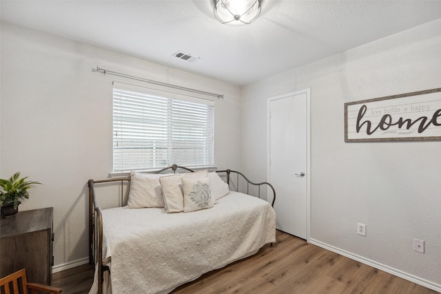 bedroom with hardwood / wood-style floors and a textured ceiling