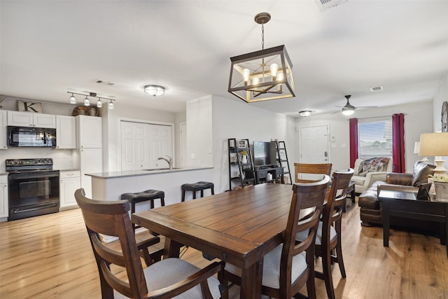 dining room featuring sink, ceiling fan with notable chandelier, and light hardwood / wood-style flooring