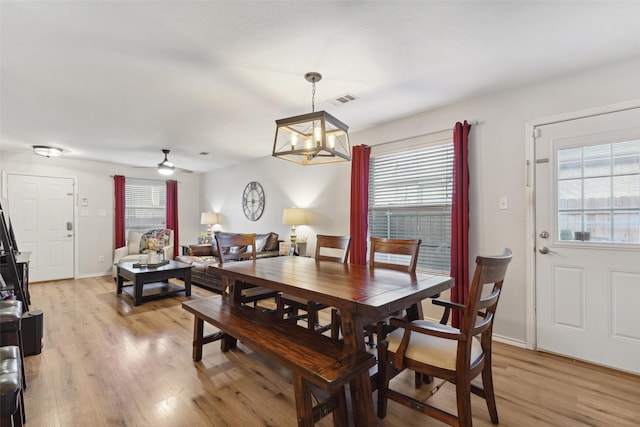 dining area featuring ceiling fan with notable chandelier and light hardwood / wood-style floors