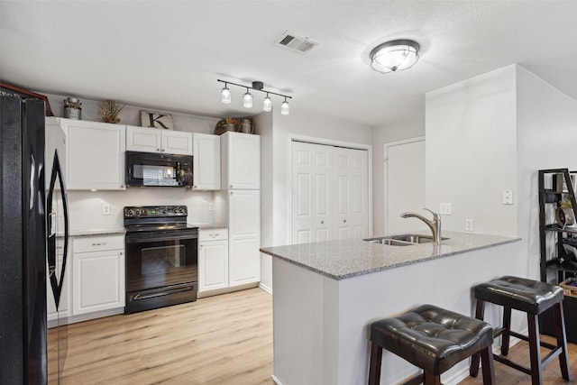 kitchen featuring white cabinetry, sink, and black appliances