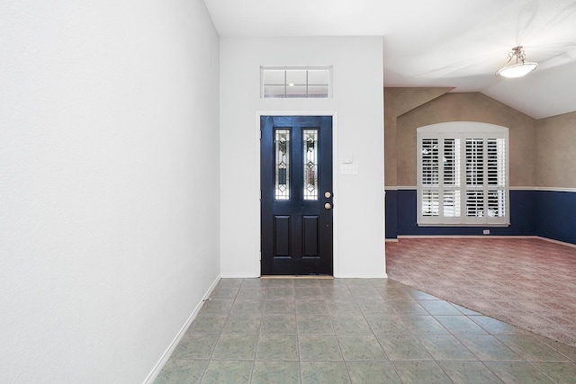 carpeted entryway with vaulted ceiling