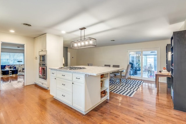 kitchen featuring white cabinetry, appliances with stainless steel finishes, light wood-type flooring, and decorative light fixtures