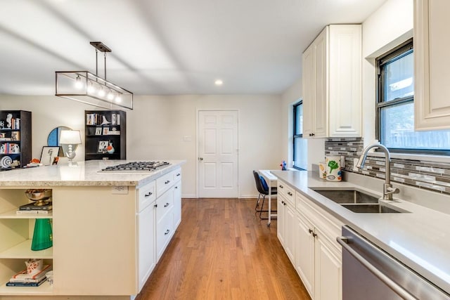 kitchen with sink, light hardwood / wood-style flooring, appliances with stainless steel finishes, pendant lighting, and white cabinets