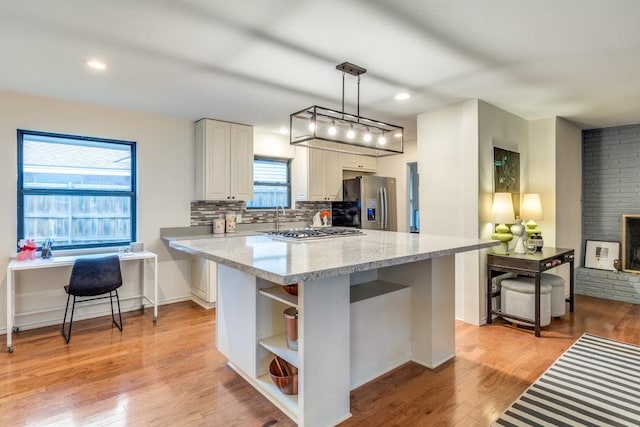 kitchen featuring white cabinetry, light stone counters, decorative light fixtures, light wood-type flooring, and appliances with stainless steel finishes