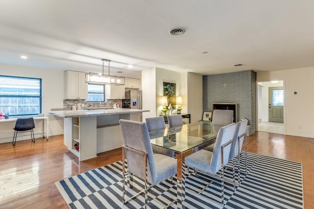 dining space featuring a brick fireplace and light hardwood / wood-style flooring