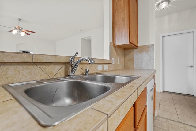 kitchen featuring sink, tasteful backsplash, tile countertops, light tile patterned floors, and white dishwasher