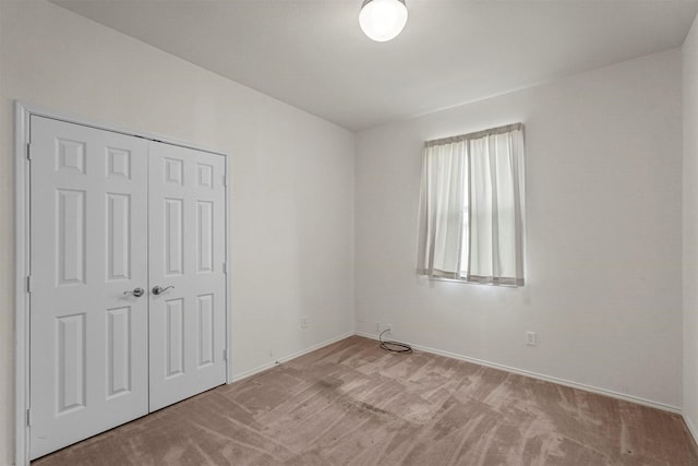 unfurnished bedroom featuring light colored carpet and a closet