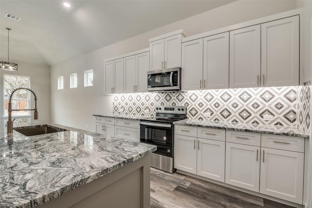 kitchen with decorative light fixtures, white cabinetry, sink, backsplash, and stainless steel appliances