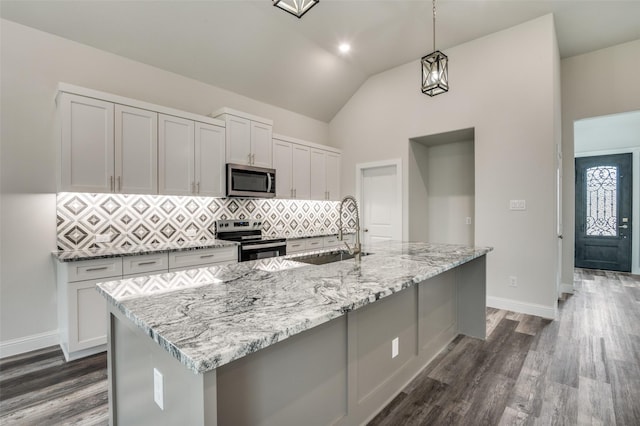 kitchen with pendant lighting, sink, a large island with sink, light stone counters, and stainless steel appliances