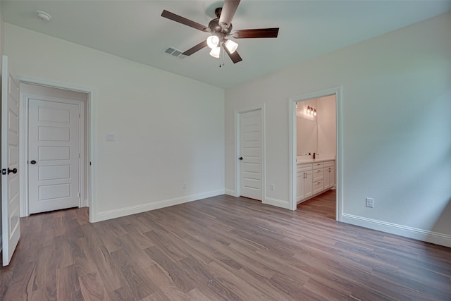 unfurnished bedroom featuring ensuite bathroom, ceiling fan, and light wood-type flooring