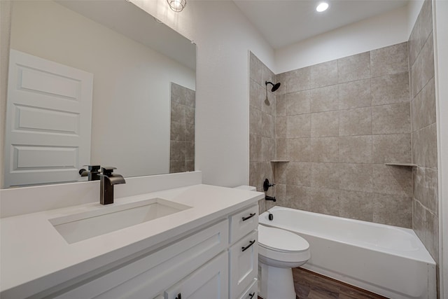 full bathroom with tiled shower / bath combo, vanity, hardwood / wood-style flooring, and toilet