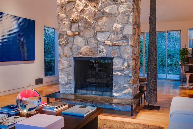 living room with hardwood / wood-style flooring and a stone fireplace