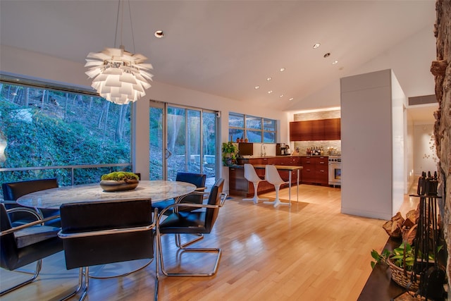 dining room featuring sink, light hardwood / wood-style flooring, high vaulted ceiling, and a chandelier