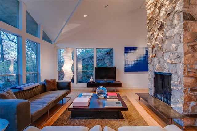 living room featuring hardwood / wood-style flooring, a fireplace, high vaulted ceiling, and a healthy amount of sunlight