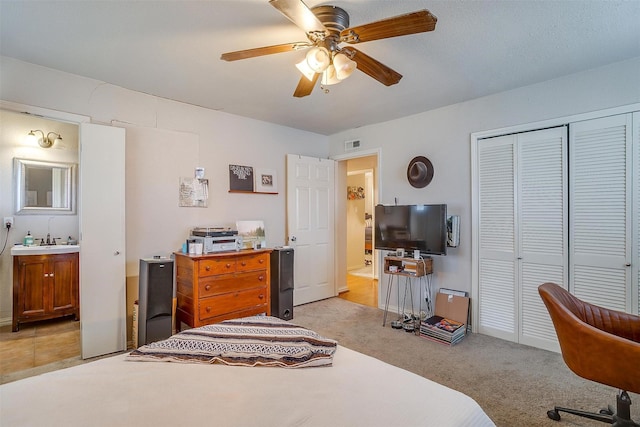 bedroom featuring sink, ensuite bath, light colored carpet, a closet, and ceiling fan