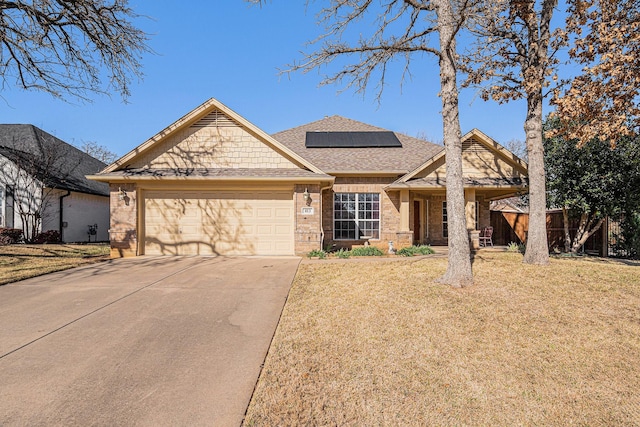 view of front of home featuring a front yard, a garage, and solar panels