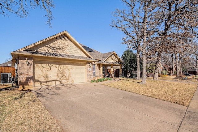 view of front of property with a garage, solar panels, central air condition unit, and a front lawn