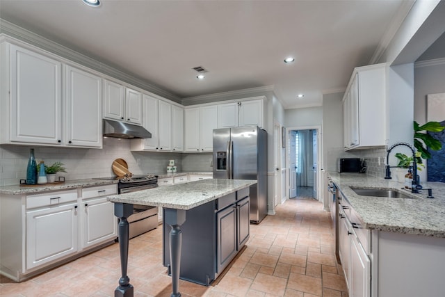 kitchen featuring sink, stainless steel appliances, a center island, and white cabinets