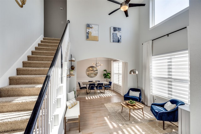 stairway featuring ceiling fan with notable chandelier, hardwood / wood-style floors, and a high ceiling