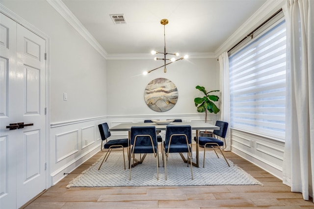 dining area with crown molding, light wood-type flooring, and a chandelier