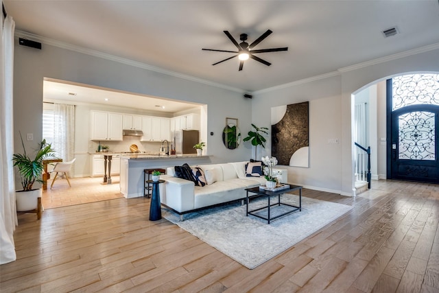 living room featuring crown molding, sink, and light hardwood / wood-style flooring