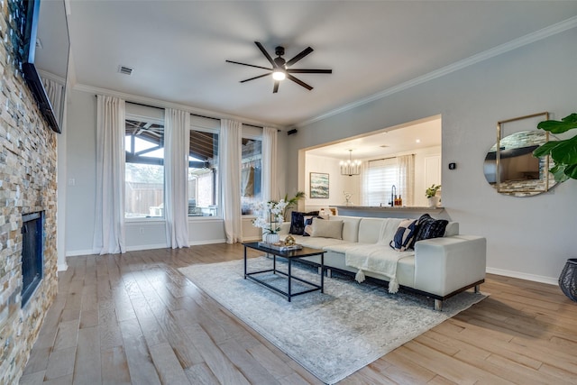 living room with crown molding, a fireplace, a wealth of natural light, and light wood-type flooring