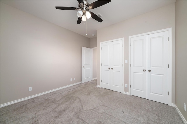 unfurnished bedroom with two closets, light colored carpet, and ceiling fan