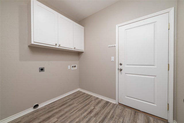 washroom featuring electric dryer hookup, hookup for a washing machine, light hardwood / wood-style floors, and cabinets