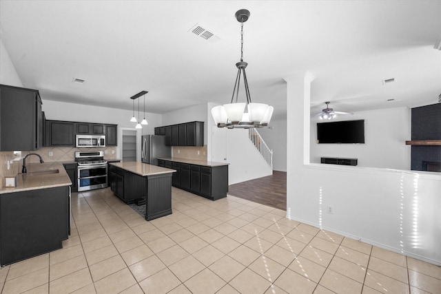 kitchen featuring sink, hanging light fixtures, light tile patterned floors, appliances with stainless steel finishes, and a kitchen island