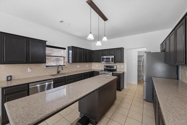 kitchen featuring sink, hanging light fixtures, appliances with stainless steel finishes, a kitchen island, and backsplash