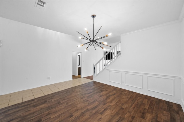 unfurnished living room with hardwood / wood-style flooring, crown molding, and a notable chandelier