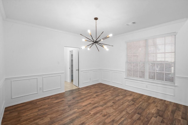 empty room featuring an inviting chandelier, hardwood / wood-style floors, and ornamental molding