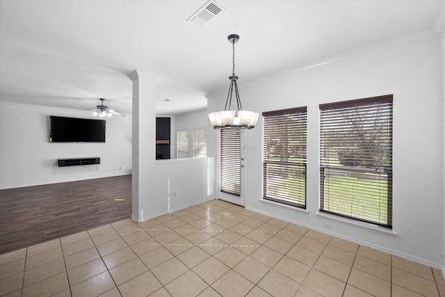 spare room featuring light tile patterned flooring and ceiling fan with notable chandelier