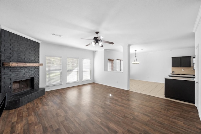 unfurnished living room with dark wood-type flooring, a fireplace, and ceiling fan with notable chandelier