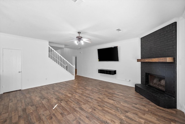 unfurnished living room with ornamental molding, a brick fireplace, dark hardwood / wood-style floors, and ceiling fan