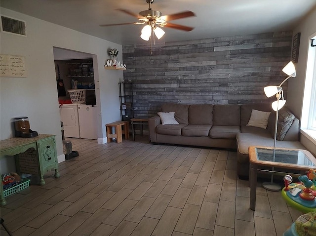 living room with wood walls, ceiling fan, and light hardwood / wood-style flooring