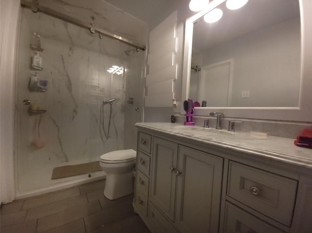 bathroom featuring vanity, tile patterned flooring, toilet, and a tile shower