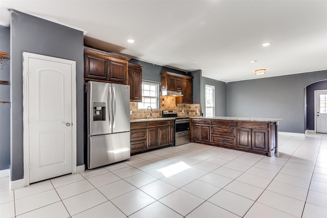 kitchen with sink, backsplash, stainless steel appliances, dark brown cabinetry, and kitchen peninsula