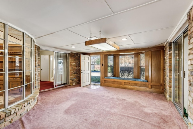 empty room with wooden walls, brick wall, and carpet flooring