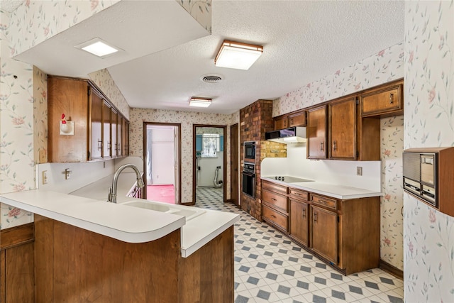 kitchen with kitchen peninsula, sink, a kitchen breakfast bar, black appliances, and a textured ceiling