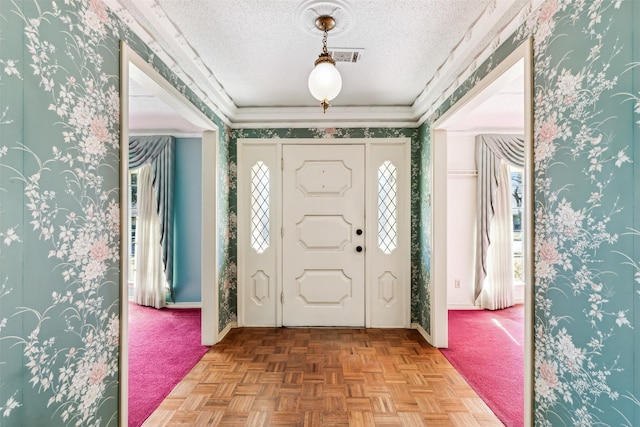 entryway featuring parquet floors, ornamental molding, and a textured ceiling