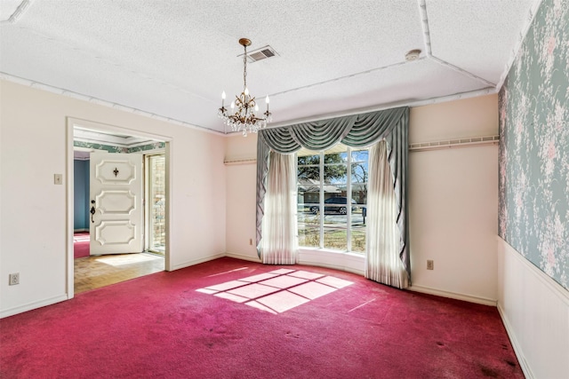 carpeted spare room featuring an inviting chandelier and a textured ceiling