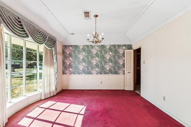 carpeted empty room featuring a notable chandelier, vaulted ceiling, and a textured ceiling