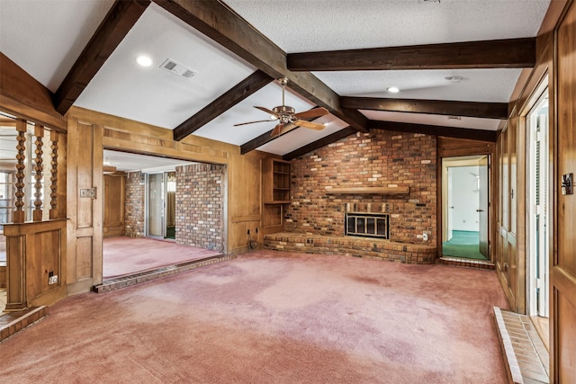 unfurnished living room featuring wood walls, lofted ceiling with beams, a textured ceiling, carpet floors, and a fireplace