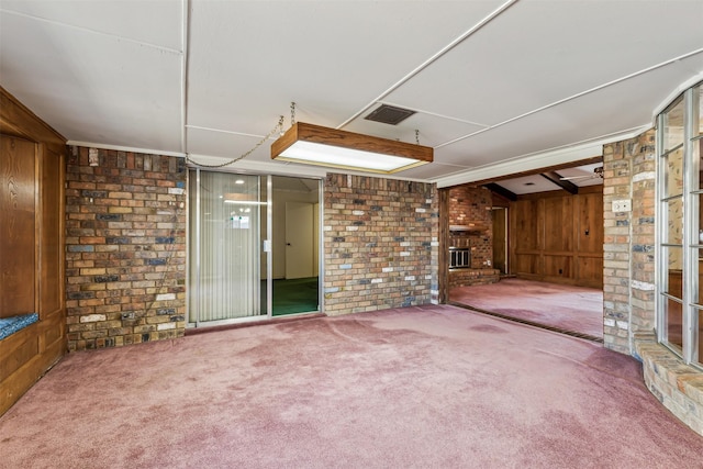 basement featuring a fireplace, brick wall, and carpet