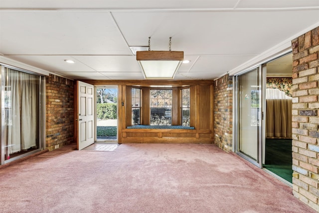 unfurnished living room with carpet floors and brick wall