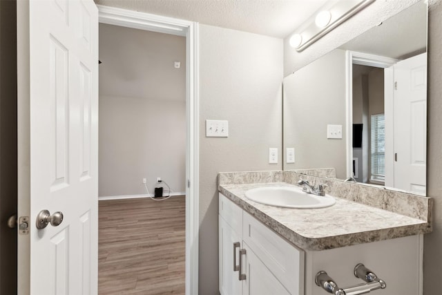 bathroom featuring hardwood / wood-style flooring, vanity, and a textured ceiling