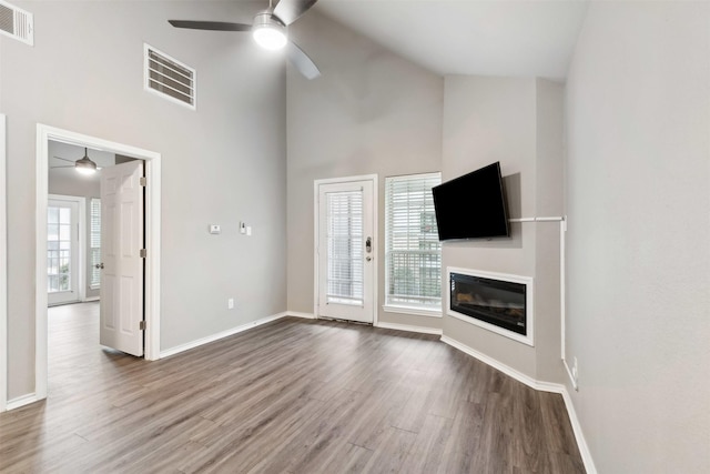 unfurnished living room with wood-type flooring, high vaulted ceiling, and ceiling fan