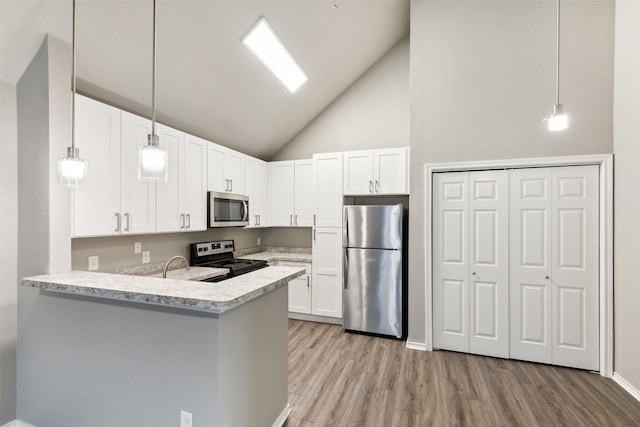 kitchen with appliances with stainless steel finishes, kitchen peninsula, hanging light fixtures, and white cabinets