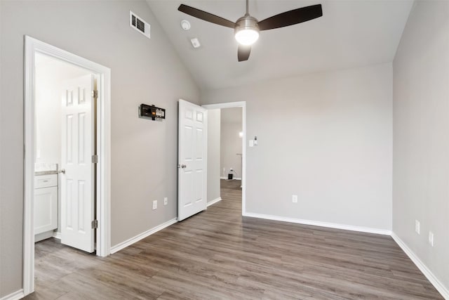 unfurnished bedroom featuring ceiling fan, ensuite bath, lofted ceiling, and hardwood / wood-style floors